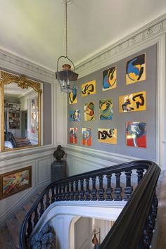 a staircase with paintings on the wall and a chandelier