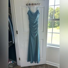 a blue dress hanging on a door in front of a window