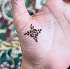 a small rose tattoo on the palm of someone's hand