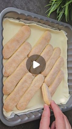 a person is holding a piece of bread in front of a pan with white frosting