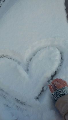 someone is holding their hand out in the snow with a heart drawn on it's side