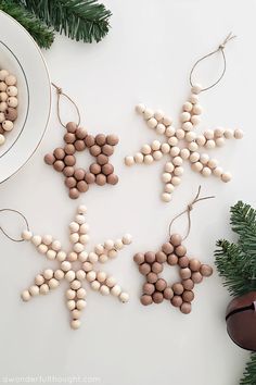 some ornaments are hanging on a table next to a bowl and potted tree branch