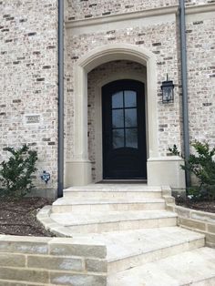 a black door is on the side of a brick building with steps leading up to it