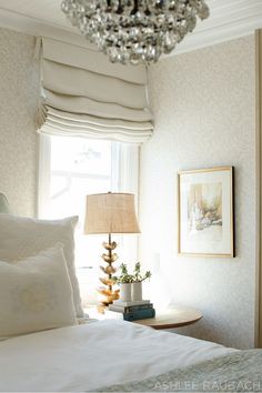 a bedroom with a chandelier hanging from the ceiling next to a white bed