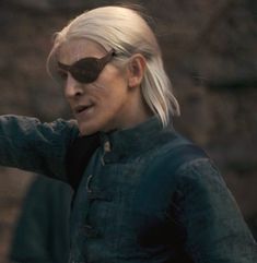 a woman with white hair and sunglasses pointing at something