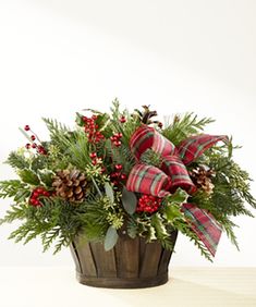 a wooden basket filled with pine cones and greenery sitting on top of a table