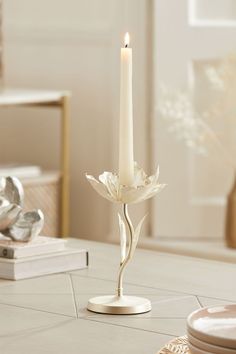 a white candle sitting on top of a table next to plates and silver utensils