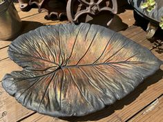 a large metal leaf sitting on top of a wooden table