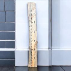 a wooden ruler sitting on top of a floor next to a white wall and black tile