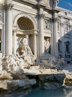 an ornate building with statues and fountains in front