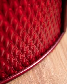 a close up view of a red snake skin bag on a wooden surface with wood grained flooring