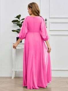 a woman in a bright pink dress is standing near a white table with a potted plant