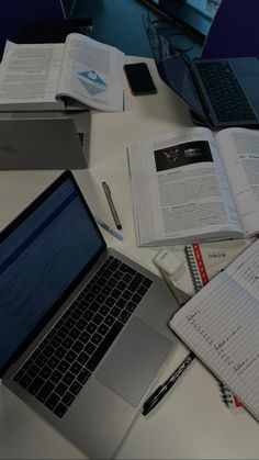 an open laptop computer sitting on top of a desk next to books and notebooks