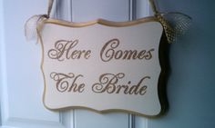 there is a sign that says here comes the bride hanging on a door handle with a bow