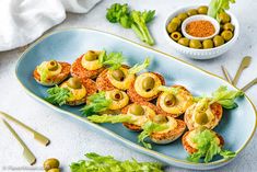 an appetizer dish with olives and lettuce on a blue platter