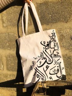 Elegant Arabic Calligraphy Takes Center Stage! Introducing our Arabic Calligraphy Tote Bag, a Fusion of Art and Fashion. Carry the Artistic Elegance of Arabic Letters with You, Symbolizing Heritage and Creativity. Let Your Style Reflect the Richness of Arabic Script, Making a Statement that Transcends Borders. Happy Shopping!🌻 🤍 open to customisation 🤍acrylics used so painting won't fade  🤍 varnished by a sealant to give shine and prevent fading. 🤍can carry a 15 inch laptop easily  🤍comes Artwork Tote Bag As A Gift, Artwork Tote Bags As Gift, Artistic Bags With Artwork For Gifts, Artistic White Rectangular Bag, Artistic White Bag For Daily Use, Artistic White Bags For Daily Use, Artistic Shoulder Bag With Artwork For Gifts, Rectangular Canvas Bag With Letter Print For Gift, Artistic White Rectangular Shoulder Bag