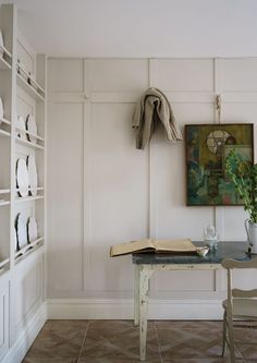 a table with a book and vase on it next to a shelf filled with books