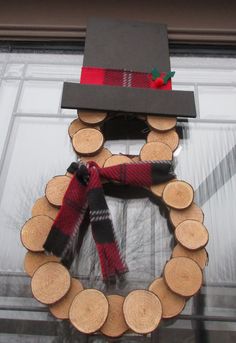 a wreath made out of wood with a hat and scarf hanging on the front door