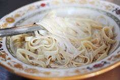 a bowl filled with noodles on top of a wooden table