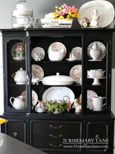 a black china cabinet with plates and flowers on it