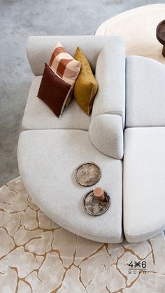 a white couch with pillows on top of it next to a coffee table and end tables