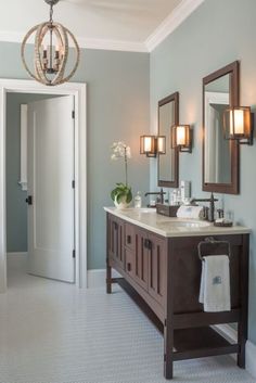 a bathroom with two sinks, mirrors and a chandelier hanging from the ceiling