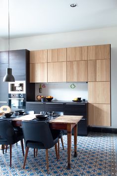 a modern kitchen with wooden cabinets and black chairs