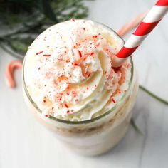 a close up of a drink with whipped cream and candy canes