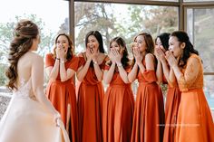 a group of women standing next to each other in front of a window with their hands on their mouths