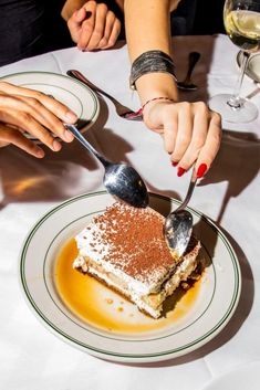 two people sitting at a table with dessert and wine glasses in front of the plate