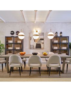 a dining room table with six chairs and a bowl of fruit on the centerpiece