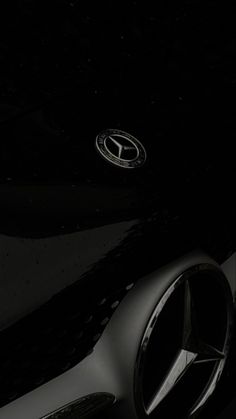 the front end of a black car with its hood up and emblems on it