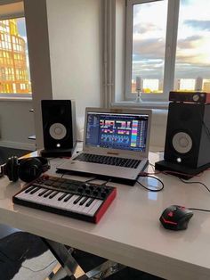 a laptop computer sitting on top of a desk next to a keyboard and sound equipment