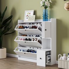 a white shoe rack with several pairs of shoes on it next to a potted plant