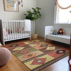 a baby's room with a crib, chair and rug