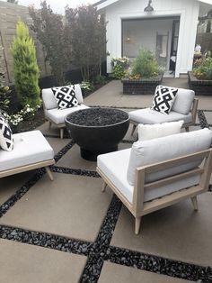 a patio with chairs, pillows and a fire pit in the center on top of it