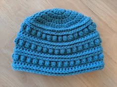 a blue crocheted hat sitting on top of a wooden floor