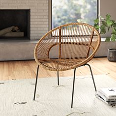 a wicker chair sitting on top of a rug in front of a fire place