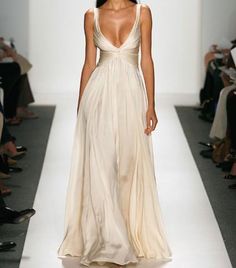 a woman is walking down the runway in a long dress with an open v - neck