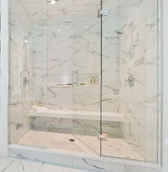 a walk in shower sitting next to a white tiled wall and floor with glass doors