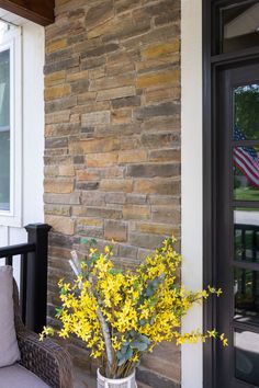 a vase filled with yellow flowers sitting on top of a porch