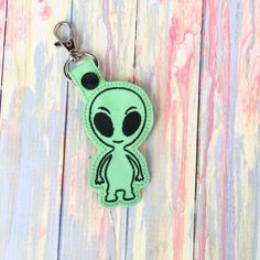 an alien keychain is shown on a wooden surface