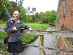 a man standing on a bridge with an umbrella over his shoulder and smiling at the camera