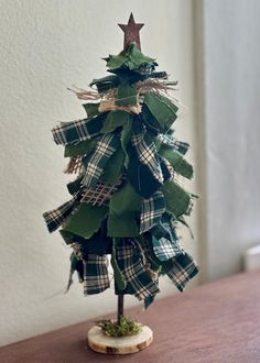 a small christmas tree made out of green paper and burlocks on a wooden table