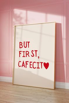 a framed poster with the words but first, cafecit on it in front of a pink wall