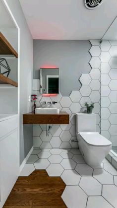 a white bathroom with hexagonal tiles on the floor and walls, along with a wooden countertop