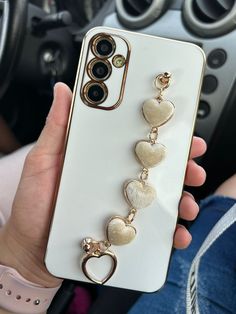 a person holding up a phone case with heart charms on it