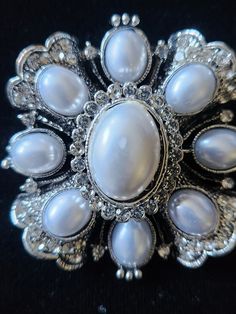 This PIN / BROOCH is a stunning silvertone CROSS set with faux BAROQUE PEARLS & clear rhinestones. NOW ON SALE (as it has a slight defect in center pearl...see pix). Still a beautiful piece, it could be be worn on a jacket, with a scarf, or at the neck of an equestrian hunt shirt or stock tie! (check out possible coordinating stock ties & points in our Etsy shop!) Add a bale and wear it as a pendant! Dressage ladies....use this STUNNER on your STOCK TIE!! Measures about 2" in diameter. Ornate White Brooches As Gift, Formal Silver Brooches With Screw Back, Elegant Silver Brooch With Screw Back, Formal Silver Multi-stone Brooches, Luxury Ornate Baroque Brooch, Stock Tie, Clear Rhinestones, Baroque Pearls, Vintage Looks