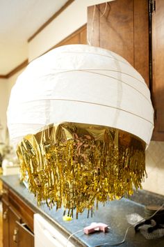 a white lamp hanging from the ceiling in a kitchen next to a stove and cabinets