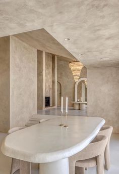 a dining room table with chairs and candles on it in front of a wall that is painted beige